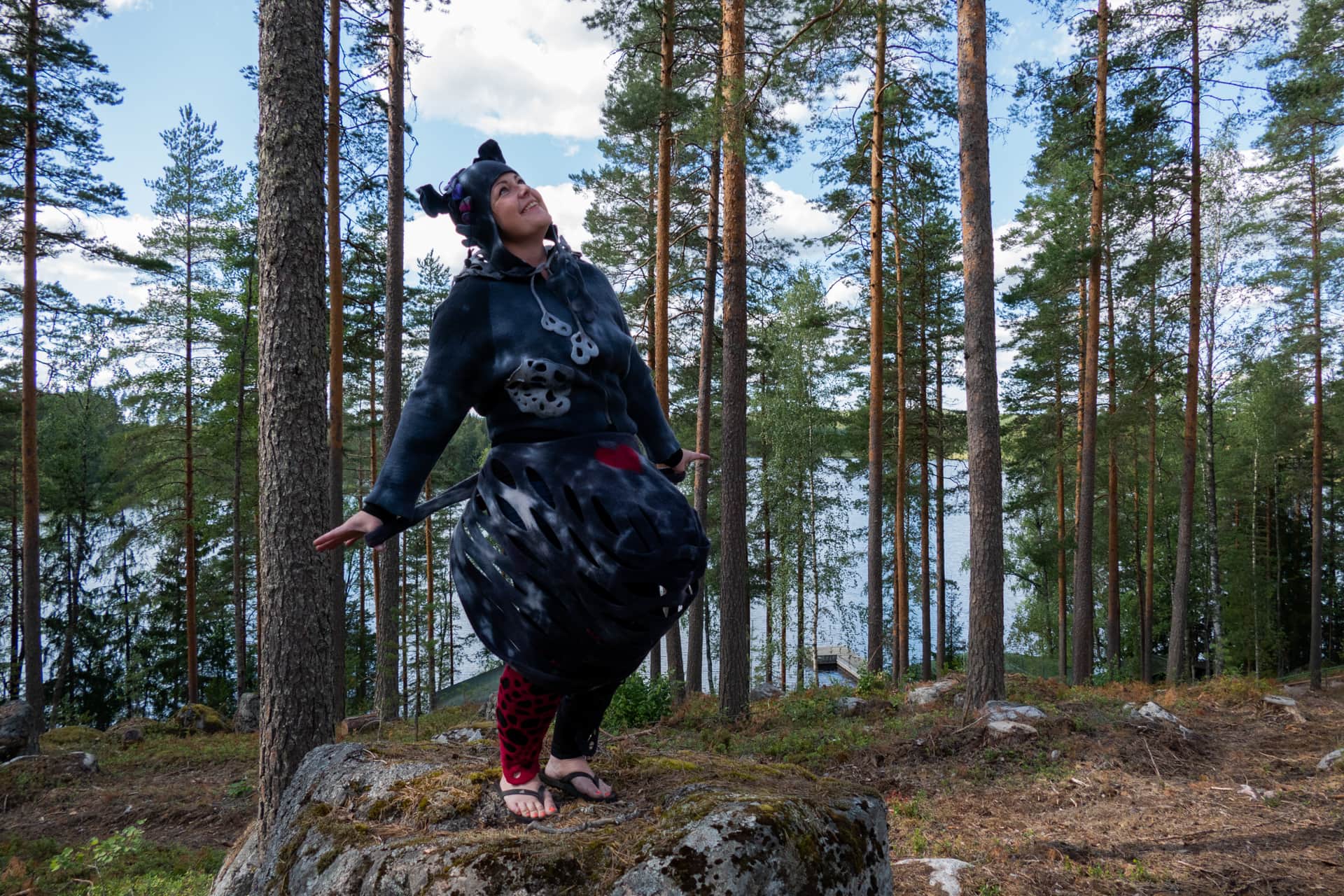 Huovutuskurssilla Elina Saaren kurssilainen poseeraa kivellä huovuttamansa vaatteet päällä.
