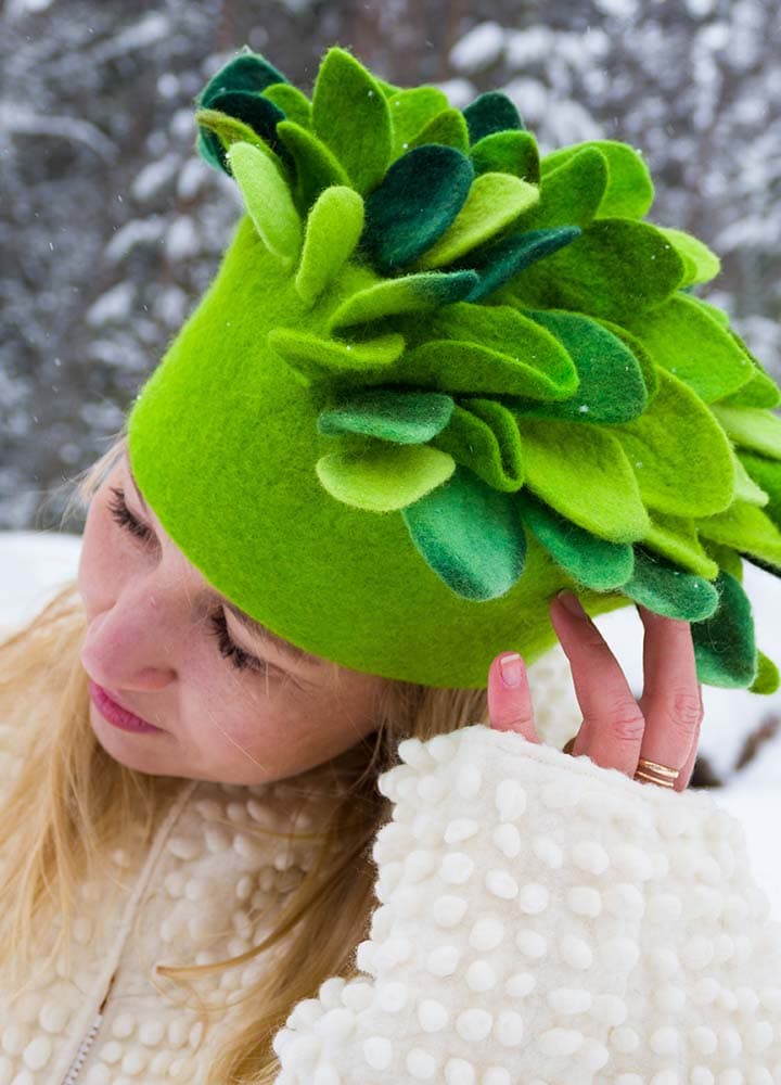 Nainen kallistaa päätä vihreä hattu päässä, jonka voi esimerkiksi valmistaa kesäkursseilla heinäkuussa.